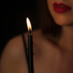 A woman smiles as she holds a lit drip candle.