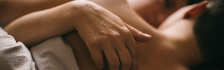 Two women hold each other tenderly on a bed.