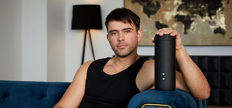 A man holds the Wild Secrets Crave 2 as he lounges contentedly on a luxe, velvet couch.